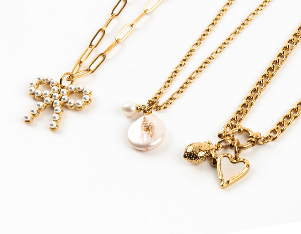 Three gold necklaces with various charms on a white background